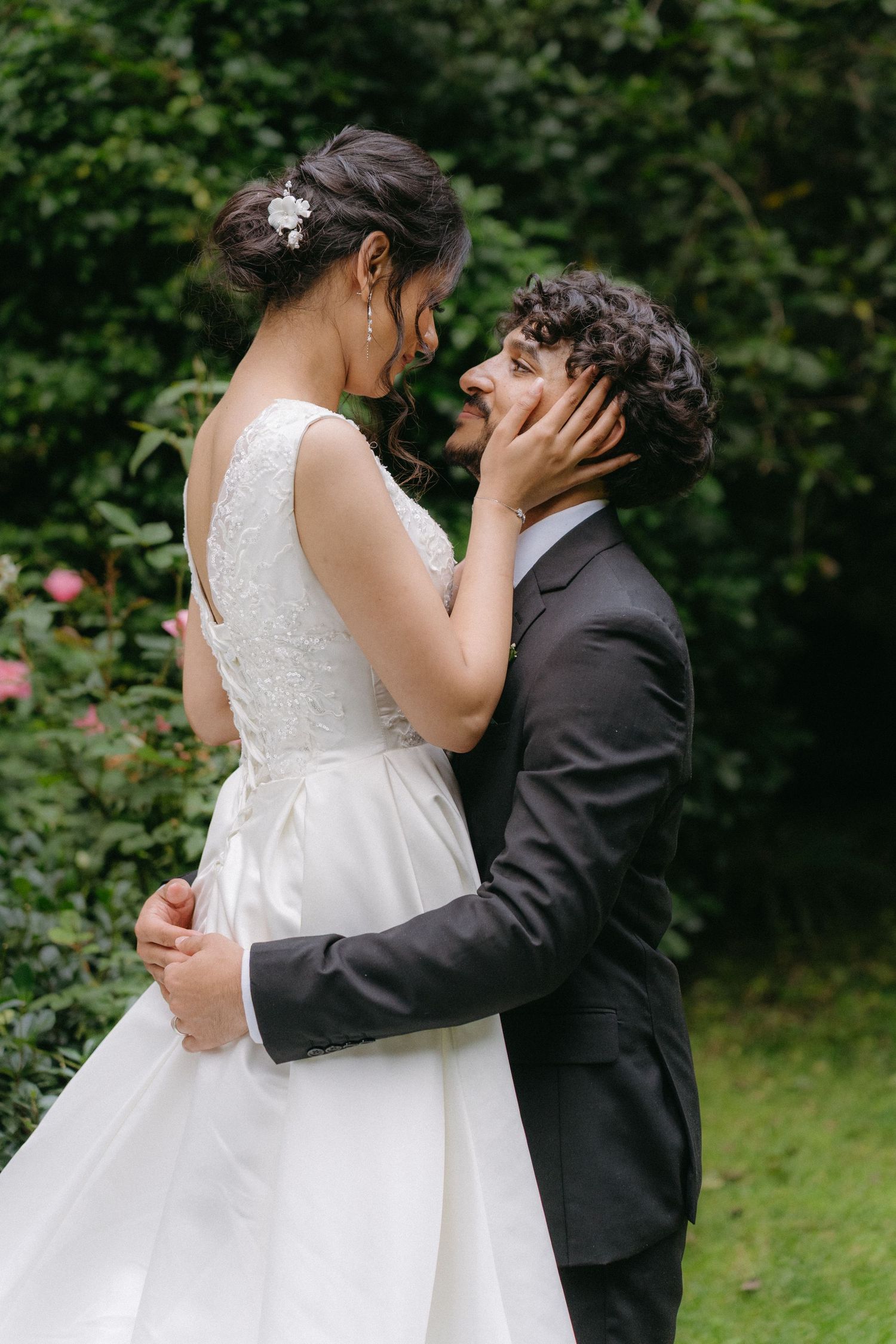 Intimate moment between newlyweds in a lush garden setting with floral details.