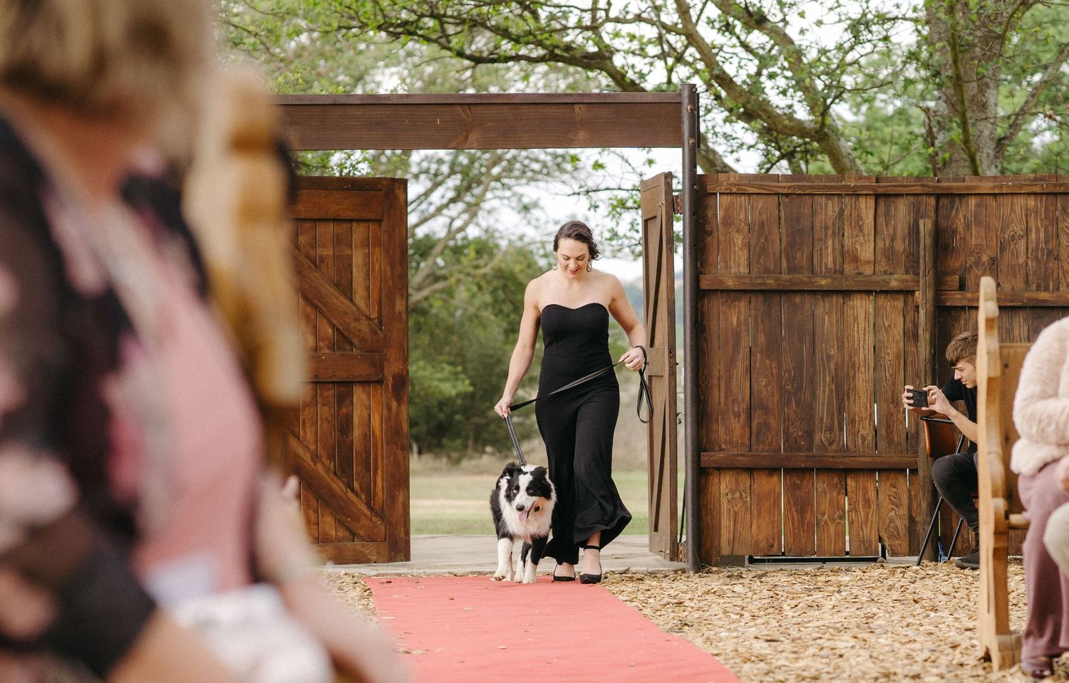 A rustic wooden barn door entrance with a red carpet walkway.