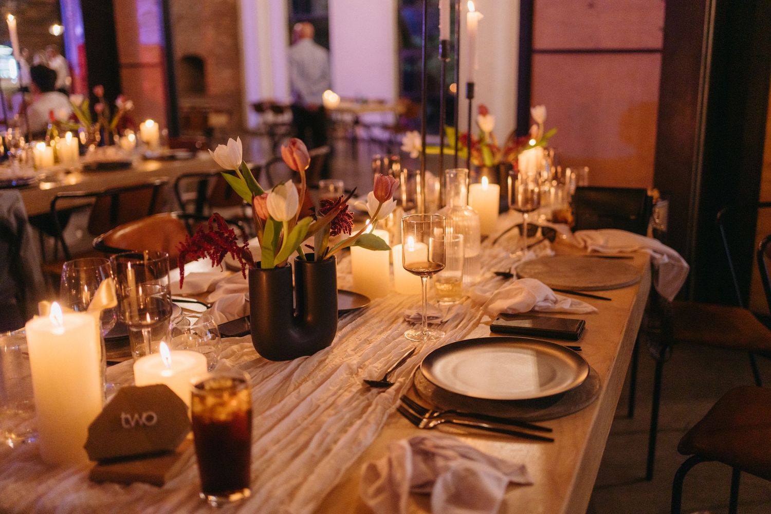Candlelit wedding reception table with rustic wooden details and elegant place settings.