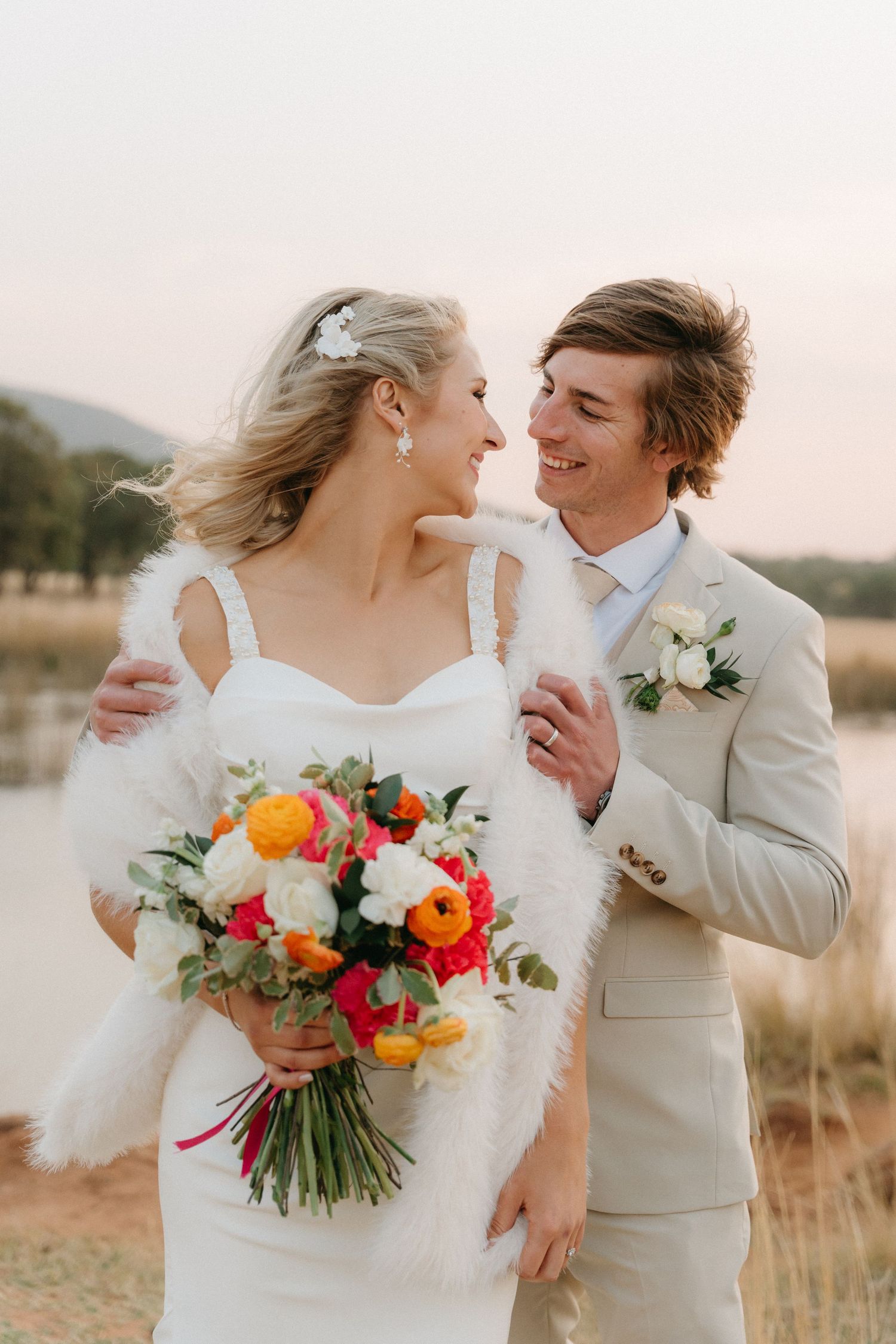Romantic outdoor wedding moment with colorful bouquet and beige suit details.