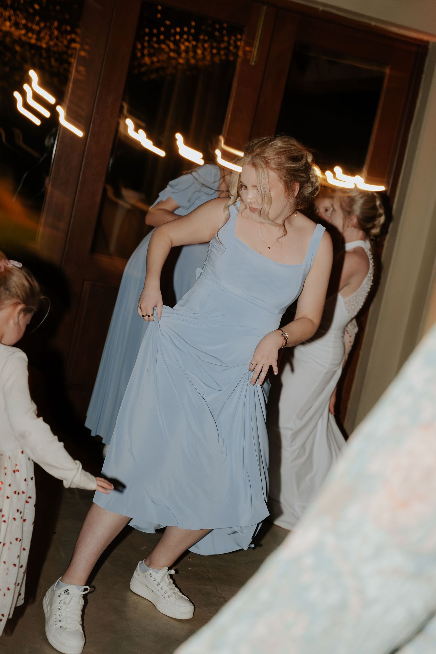Wedding party in light blue dresses dancing and celebrating at an indoor reception.