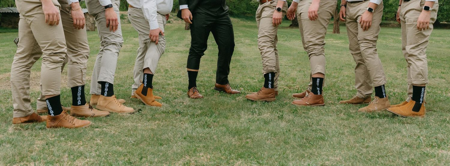 Wedding party members show off their colorful socks in a fun group photo.