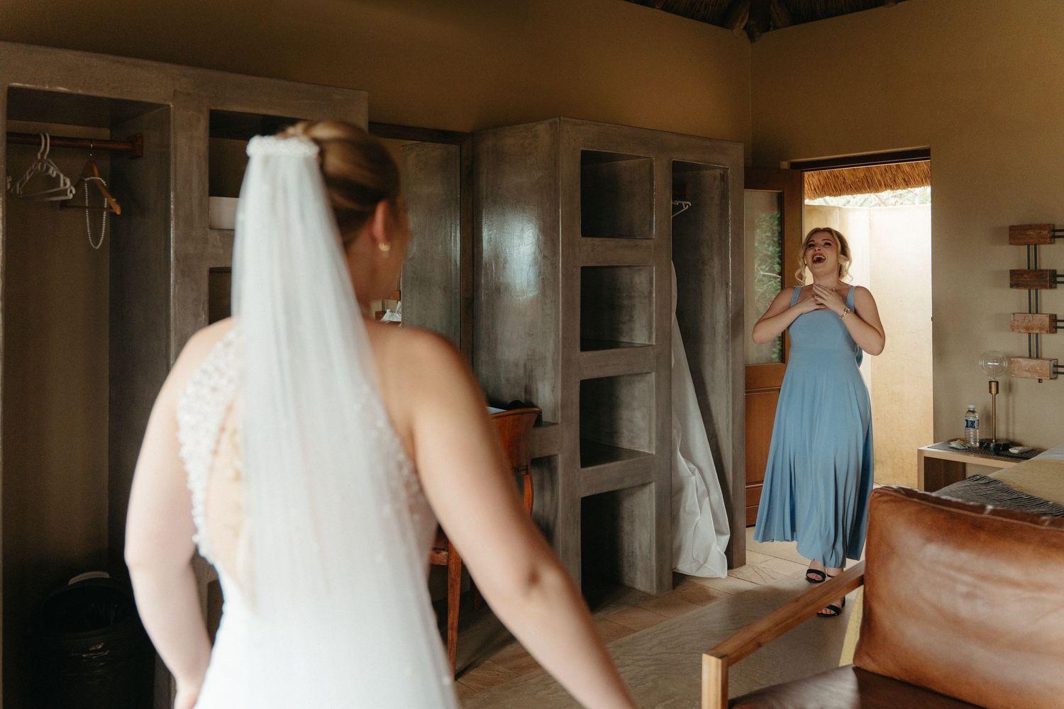 A wedding dress preparation scene with two people in a rustic interior setting.