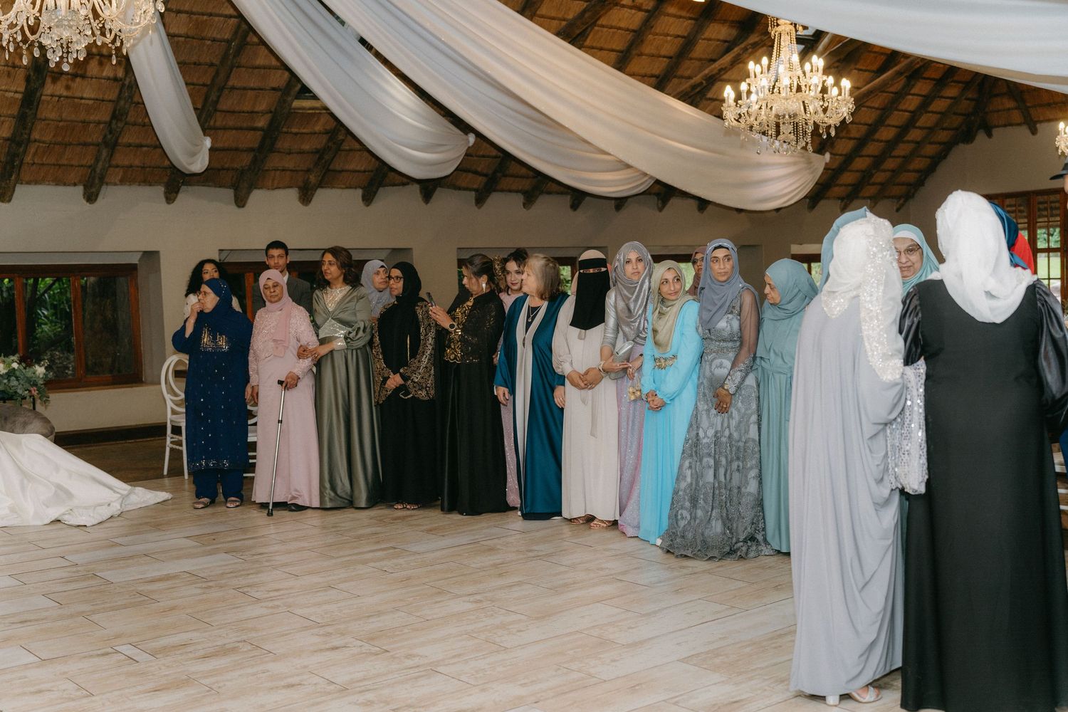 Wedding guests in formal traditional dress standing in line at an elegantly decorated reception venue.