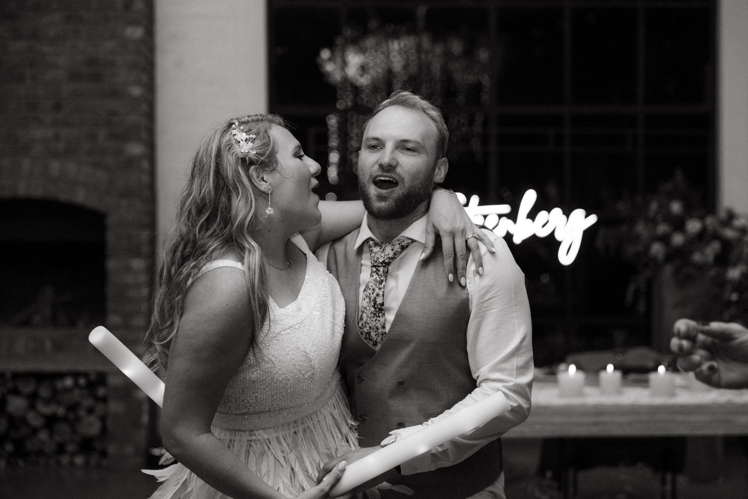 Black and white photo of a couple sharing a joyful moment at their reception.