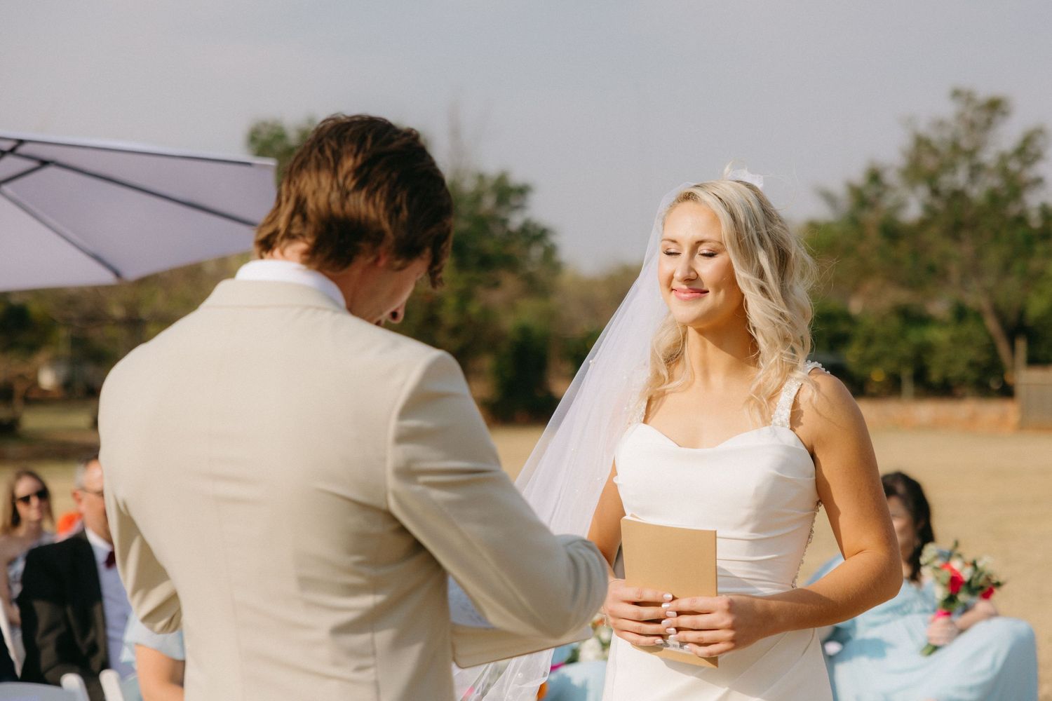 Couple embraces during romantic outdoor wedding photos with desert landscape in background.
