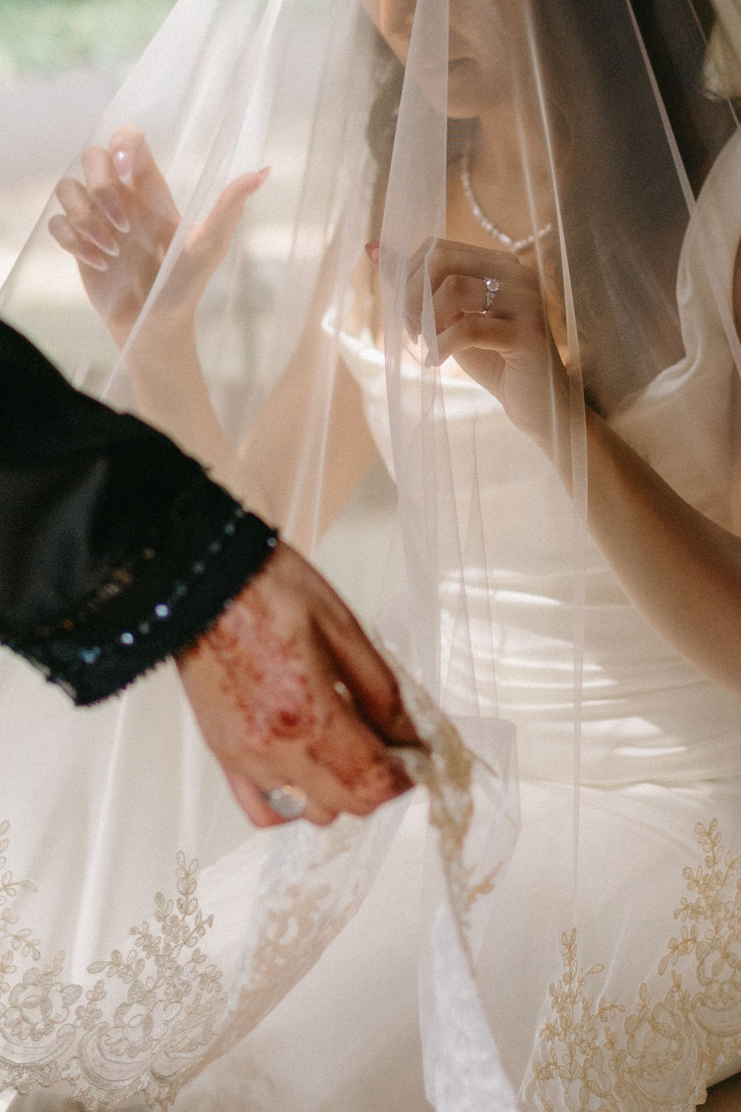 Close-up detail of delicate lace veil and hands during wedding ceremony.