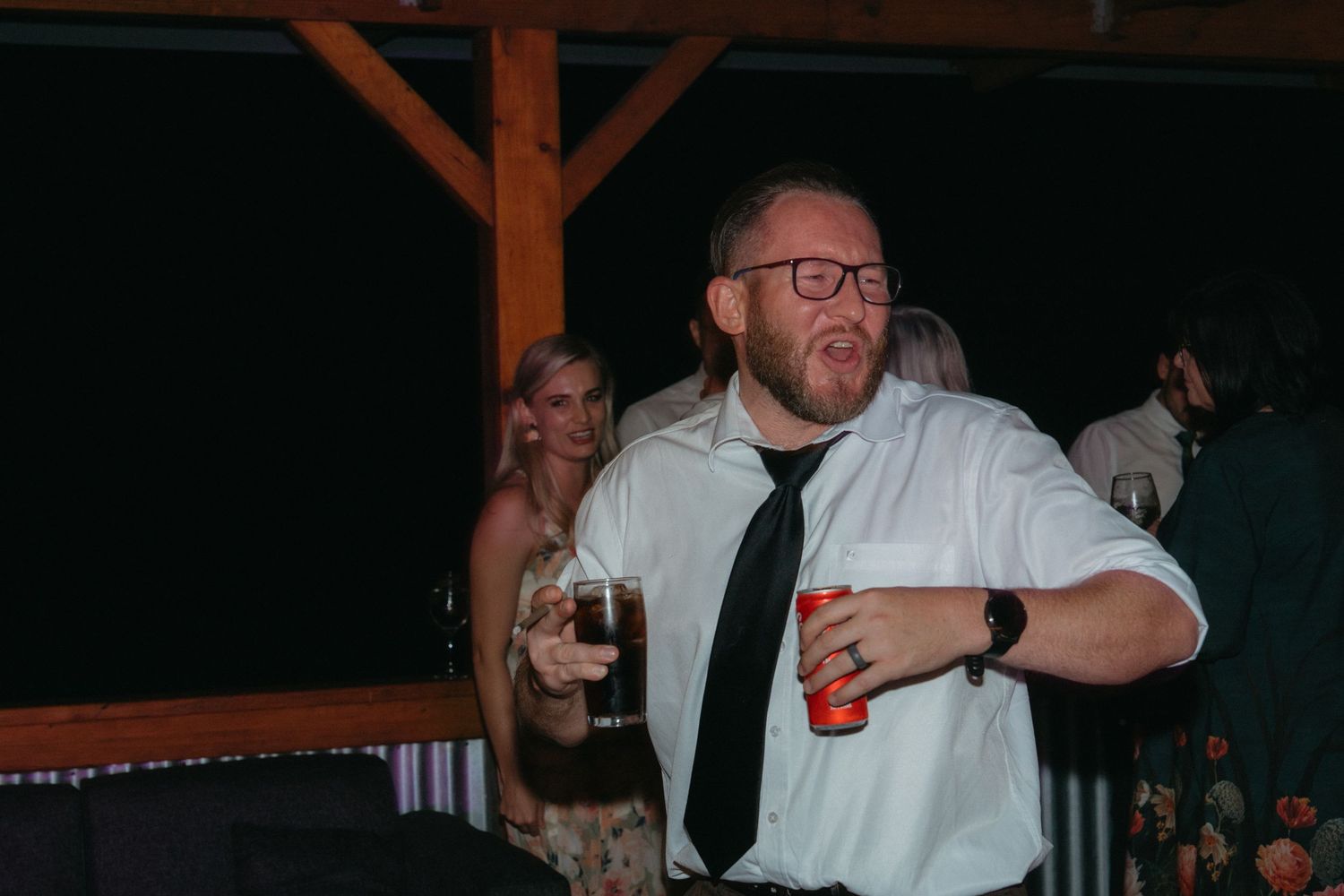 Man in formal attire enjoying drinks and dancing at a festive evening celebration.