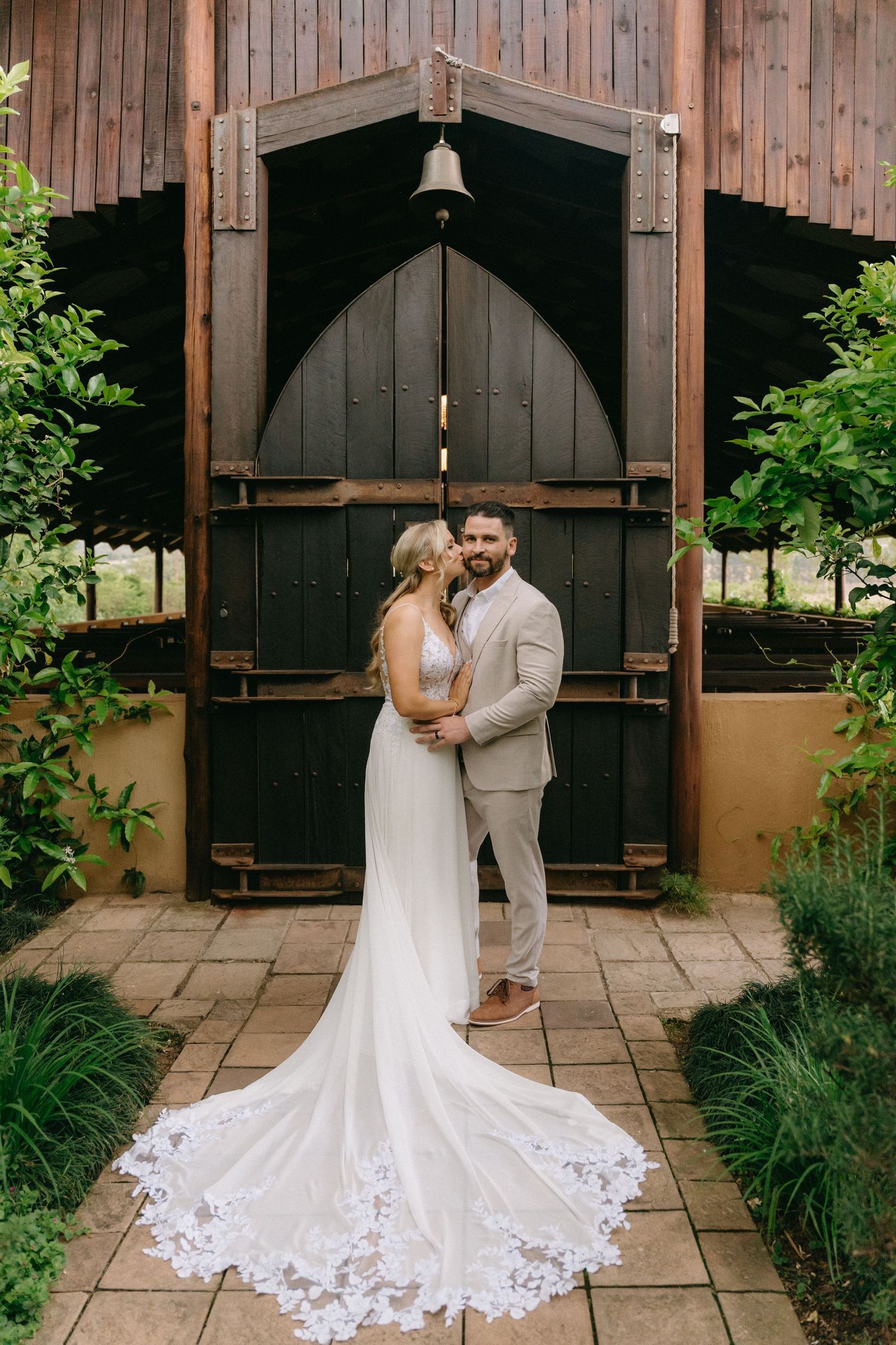 A romantic wedding moment captured in a rustic wooden chapel with beautiful lace dress details.