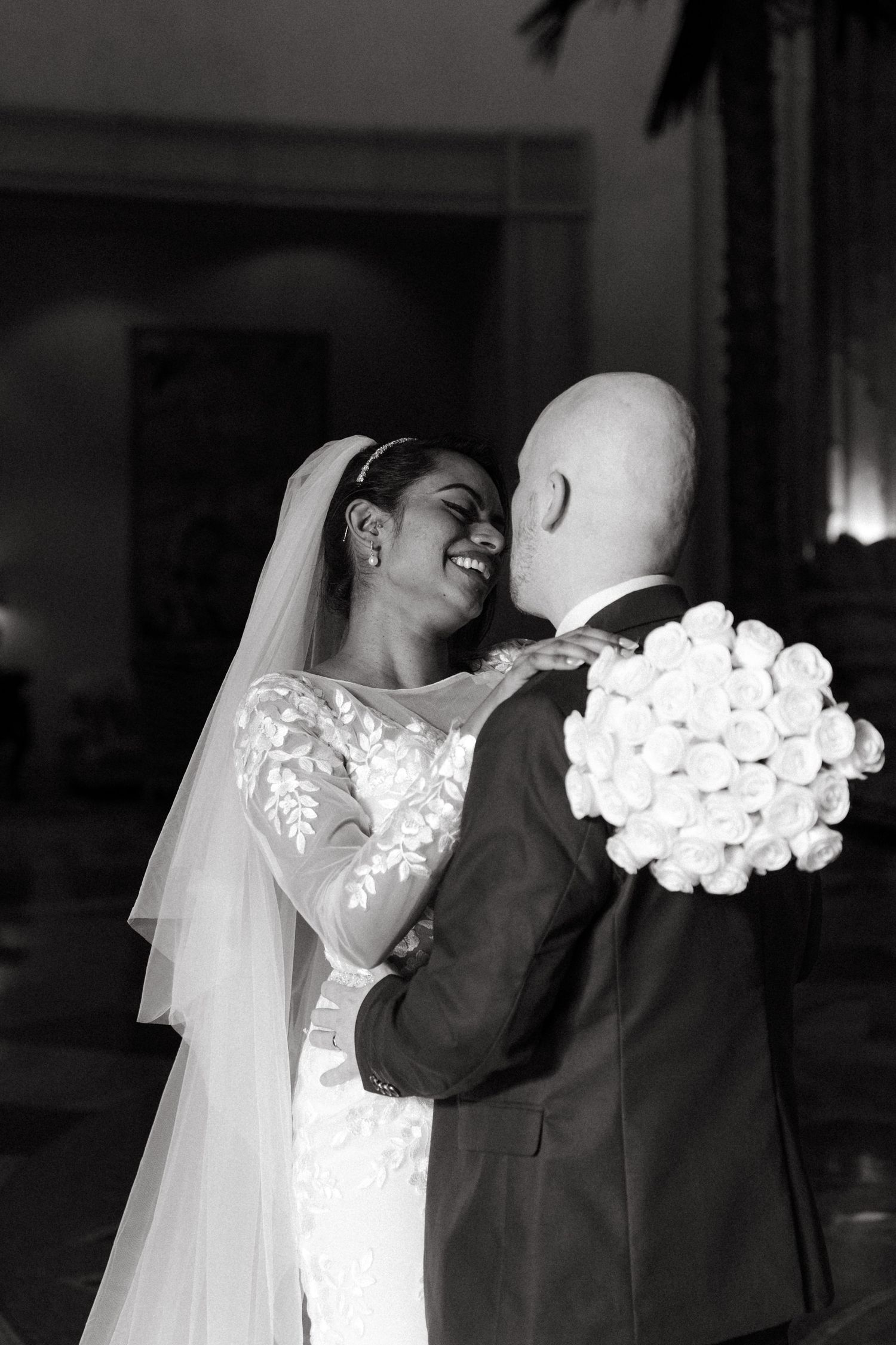 A romantic black and white wedding photo shows the happy couple embracing with white roses.