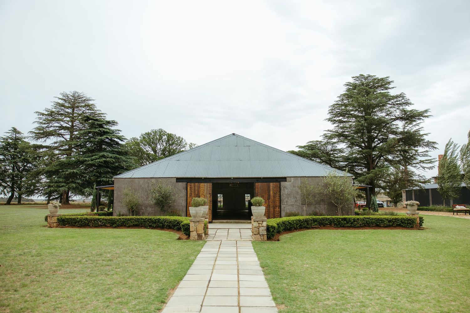 Modern gray wedding venue with manicured lawn and pathway leading to entrance.