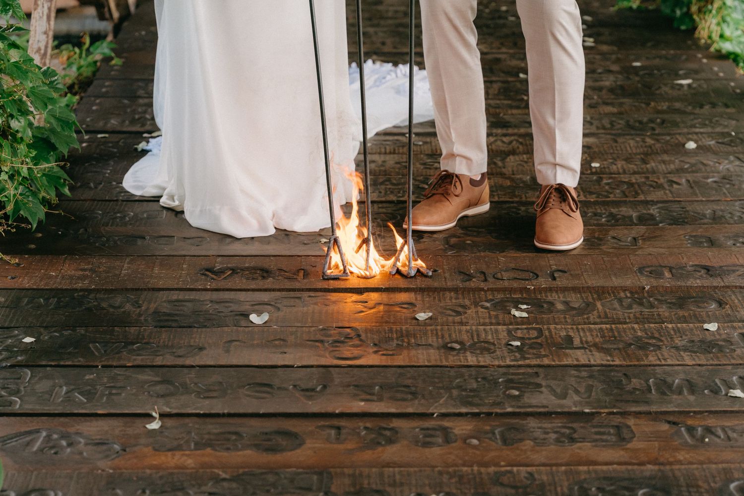 Wedding party members' feet lined up on rustic wooden deck with candle light.