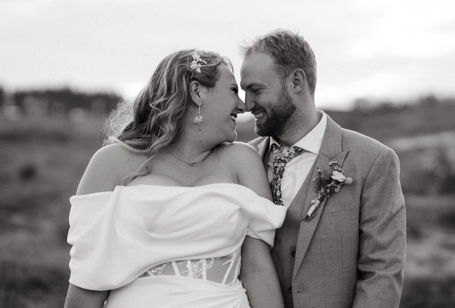 A romantic black and white wedding photo of a happy couple sharing an intimate moment in a scenic outdoor setting.