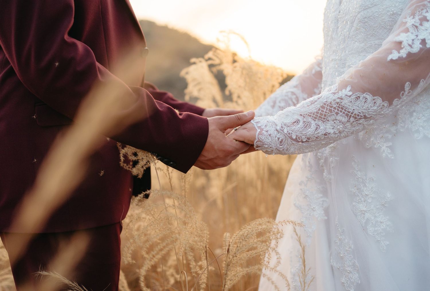 Close-up of hands holding delicate white lace fabric with intricate floral patterns in warm lighting.