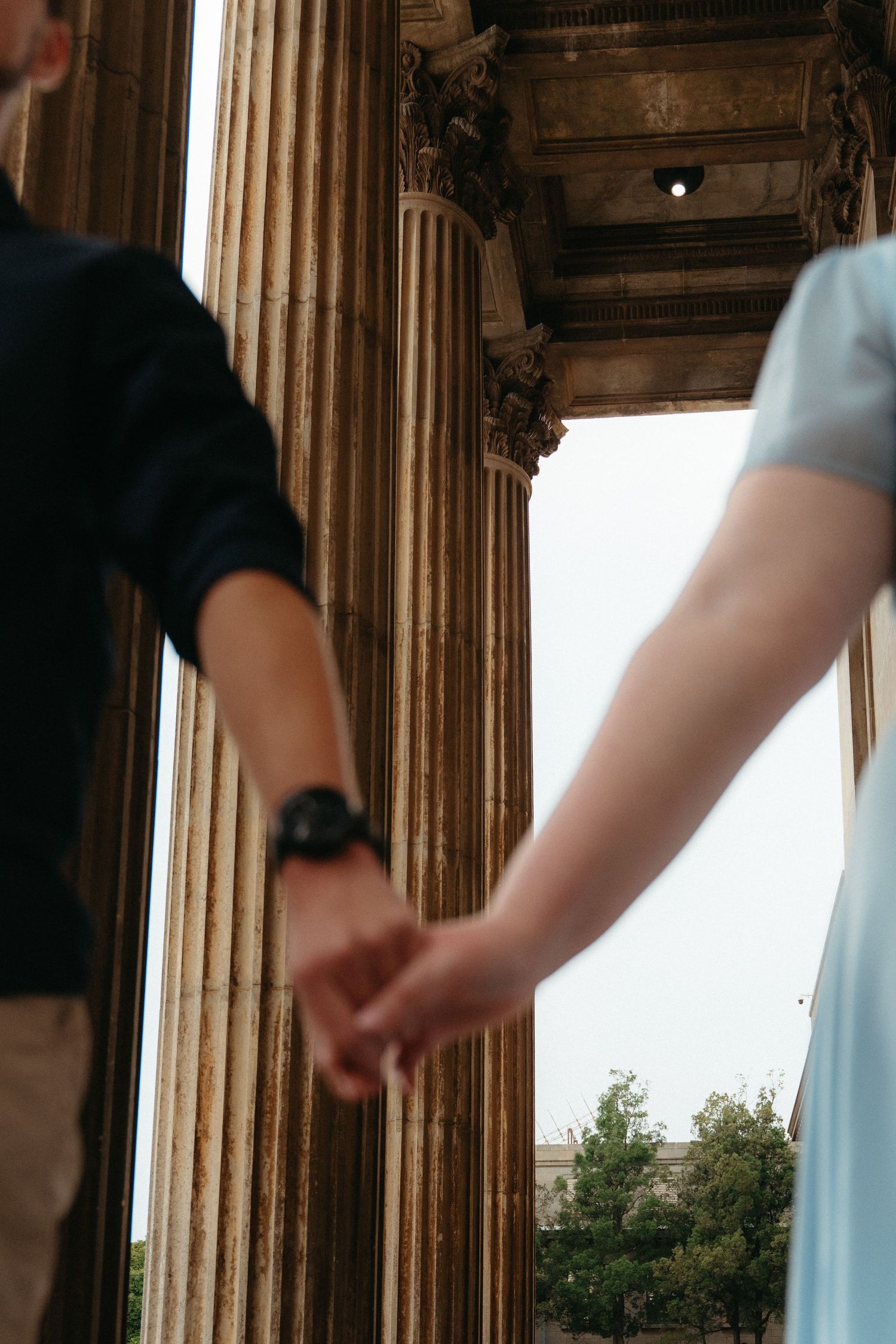 A sequence of images showing hands reaching between classical stone columns at different angles.