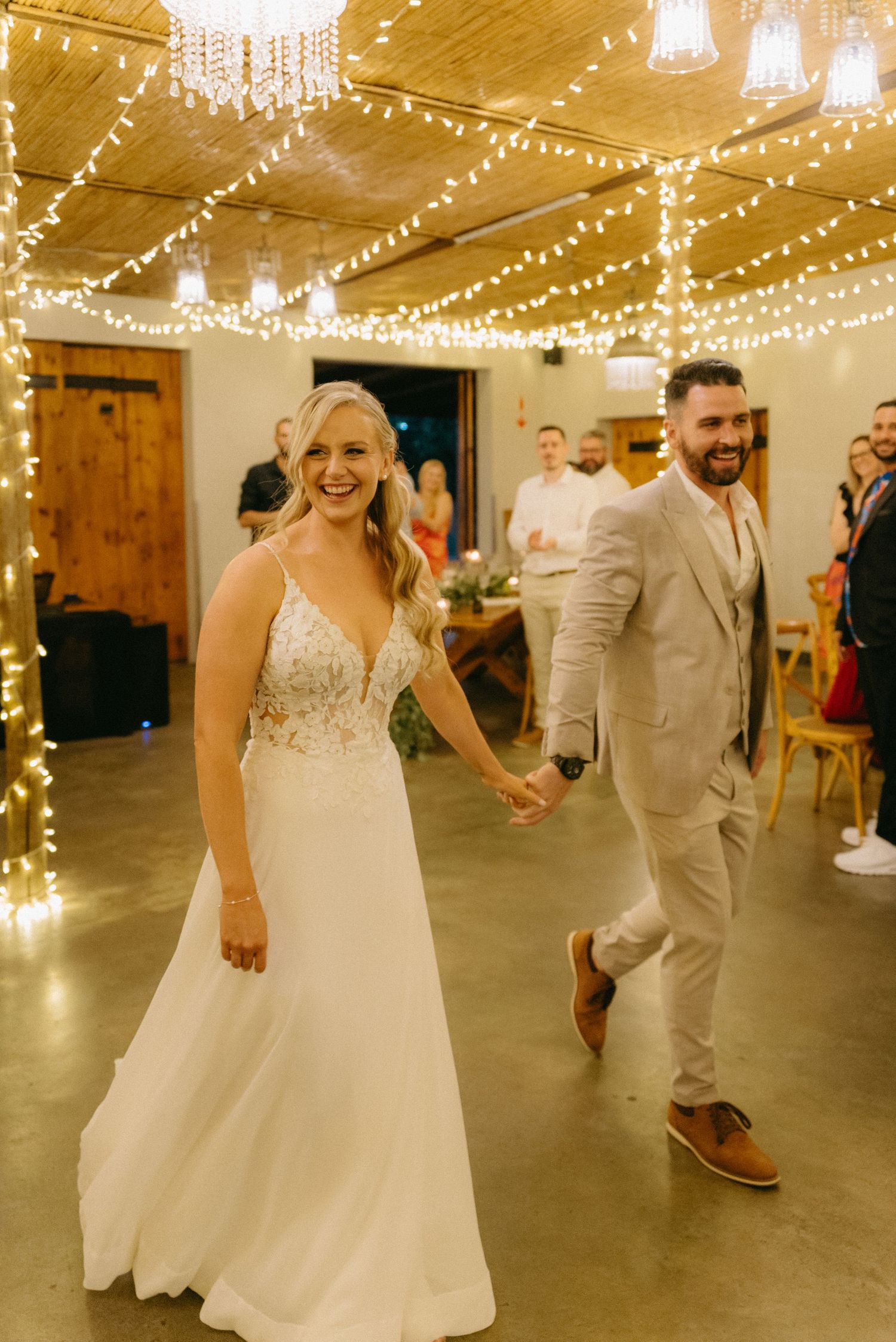 A couple dances under twinkling string lights during their wedding reception.