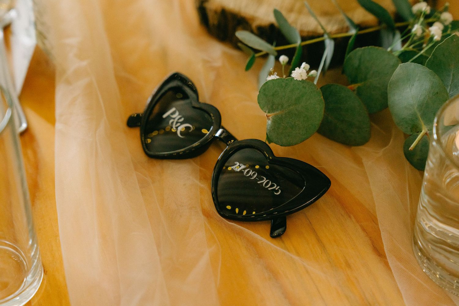 Wedding decorations and greenery arranged on wooden surface.