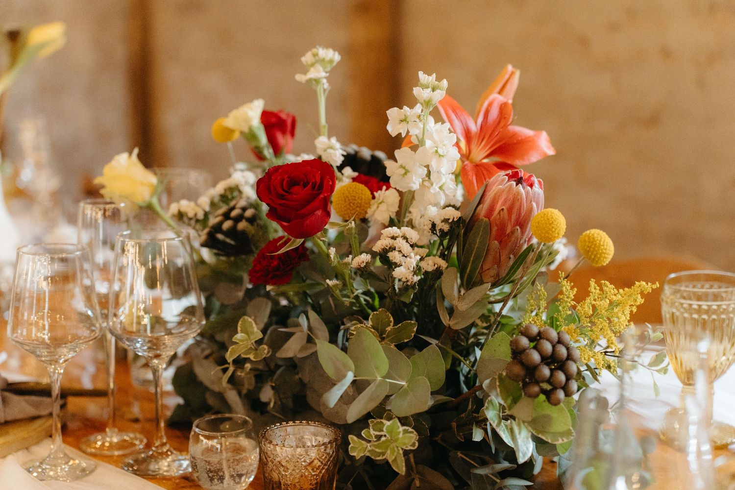 Elegant wedding table setting with colorful floral centerpiece and glowing candles.