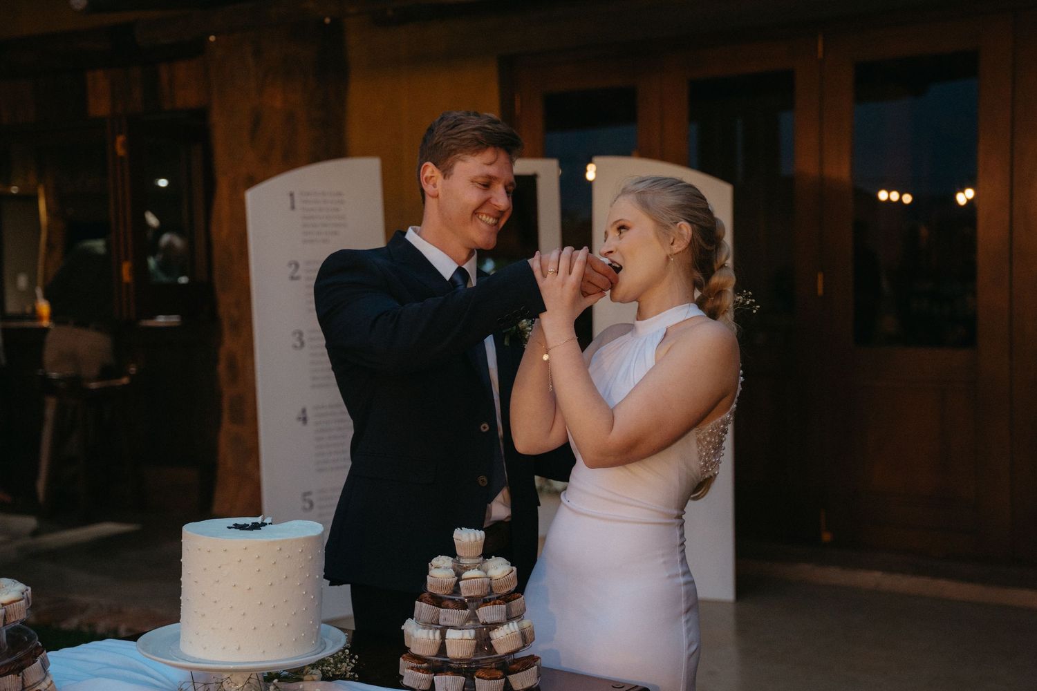 Newlywed couple shares their first bite of wedding cake together at their reception celebration.