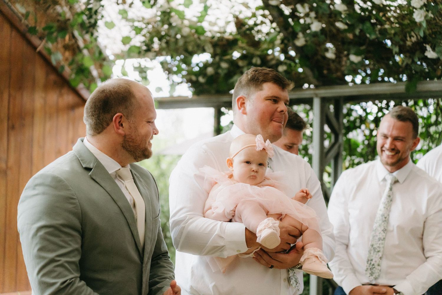 Wedding party members gathered on outdoor patio during daytime celebration.