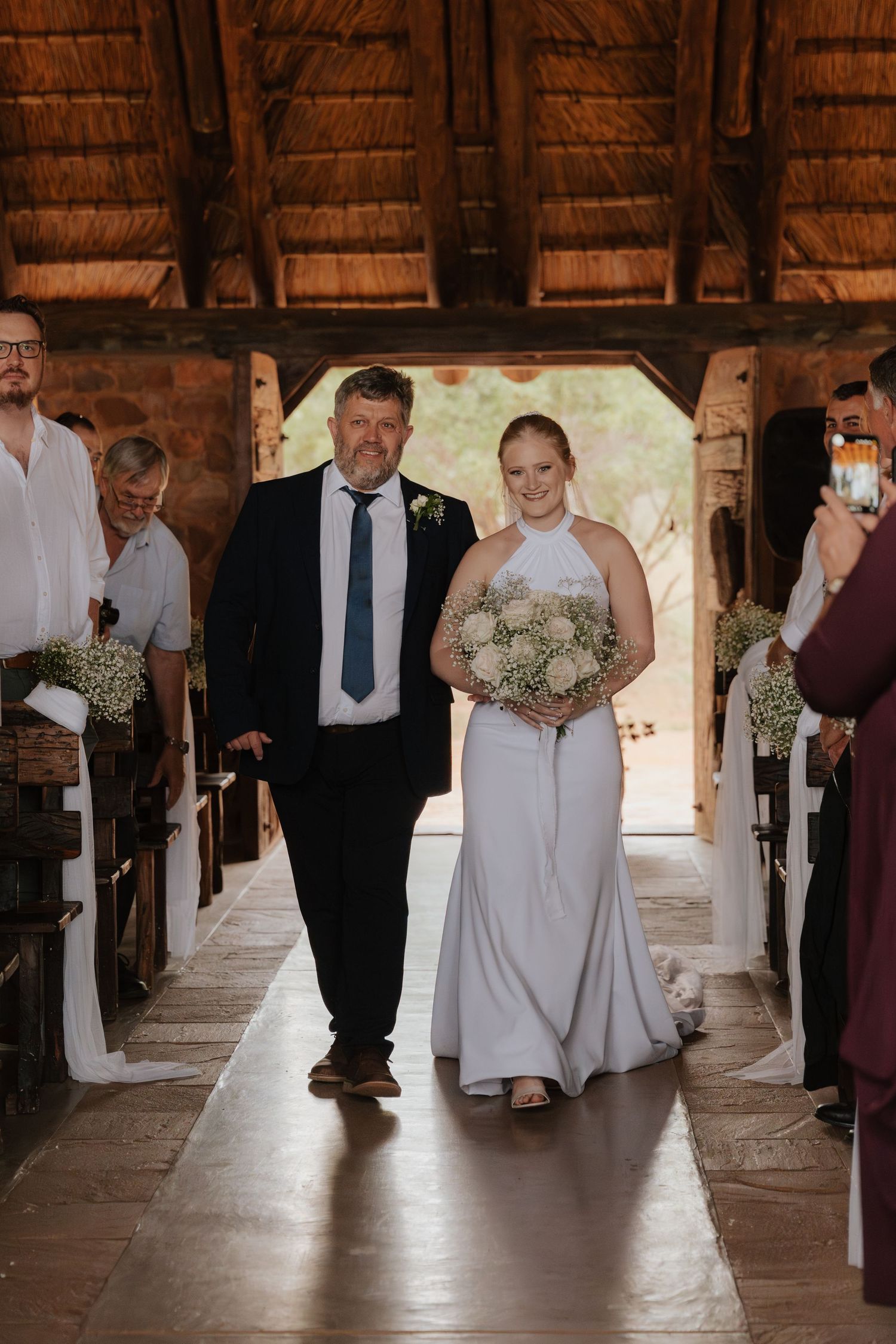 Wedding party members walking down the aisle in a rustic wooden barn venue.