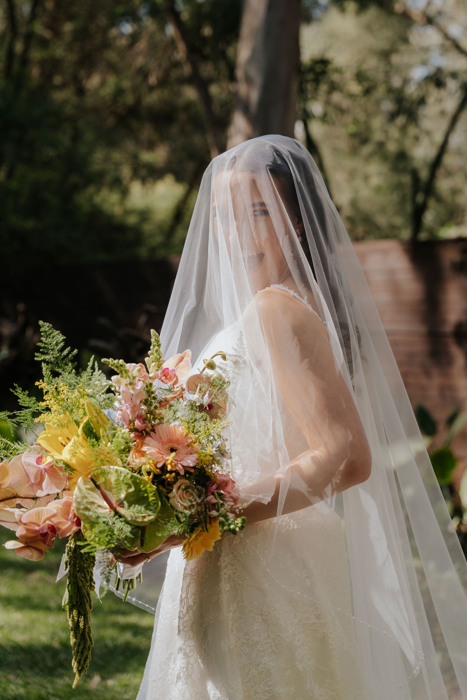 A series of wedding photos showing a bride in a white dress and veil holding a colorful wildflower bouquet in sunlit garden.