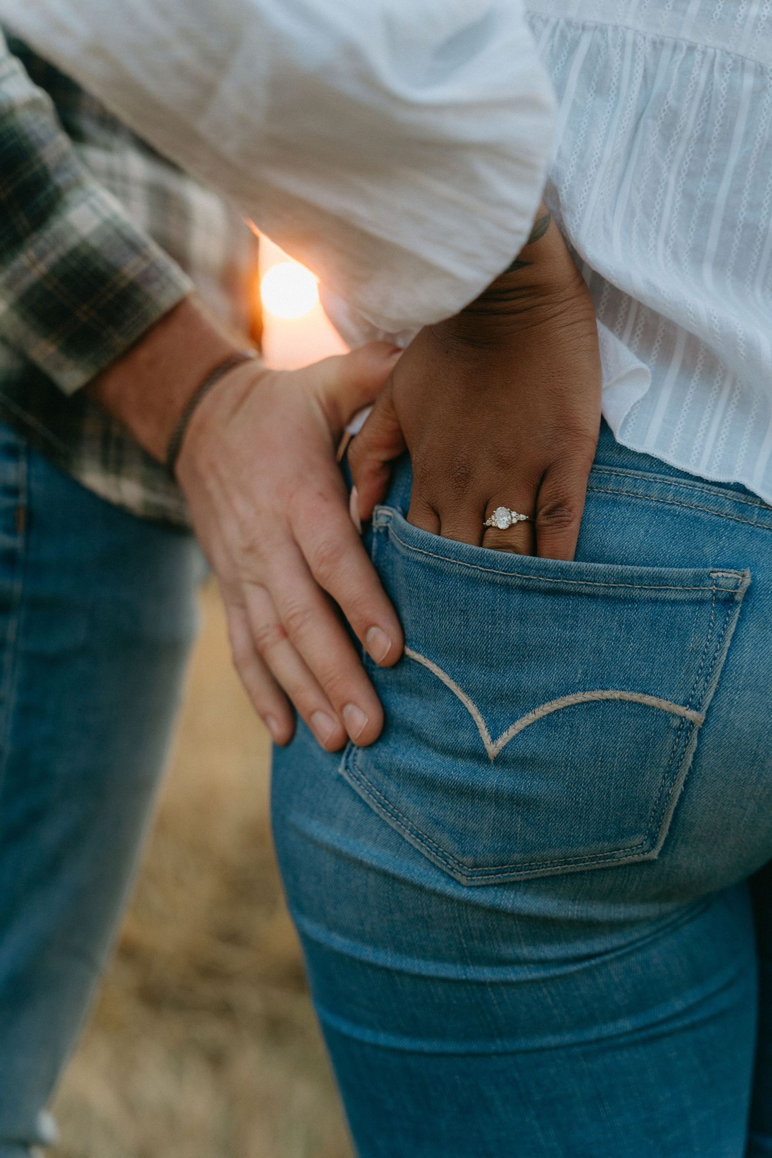 Close-up of hands putting something into the back pocket of blue denim jeans.