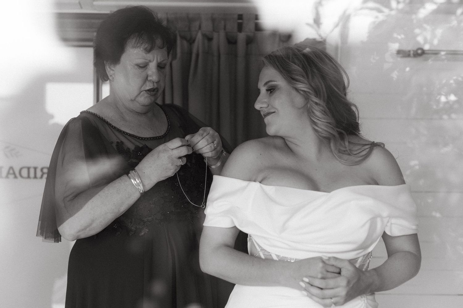 Black and white image of final wedding dress preparations in a private moment.