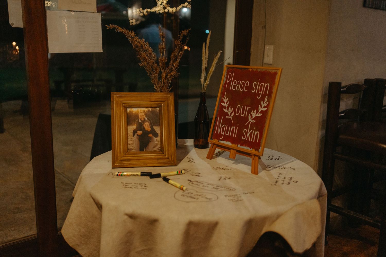 A decorated table with a vintage frame and signage at a wedding event.