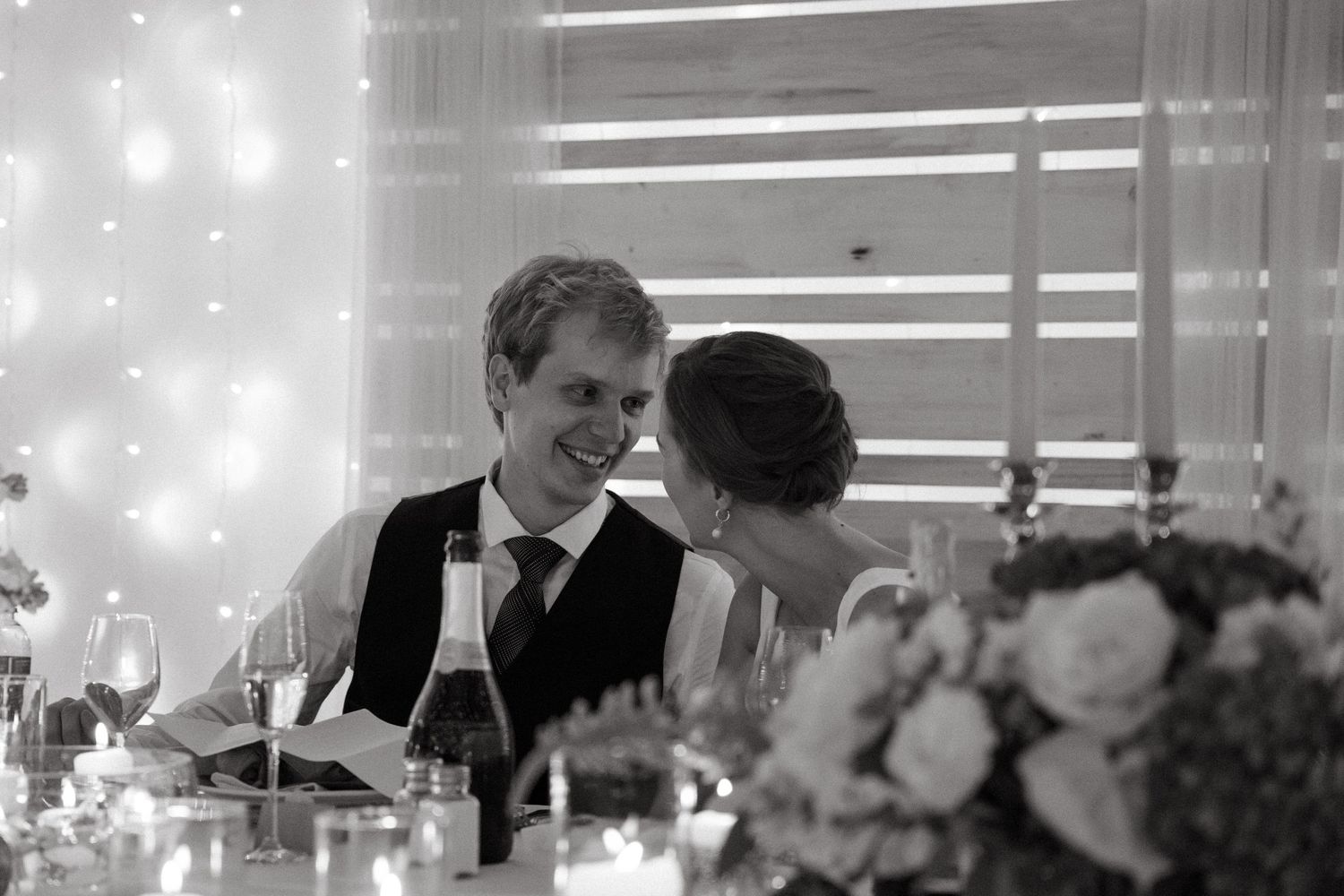 Wedding guests dancing and celebrating at an elegant indoor reception with twinkling lights and decorations.