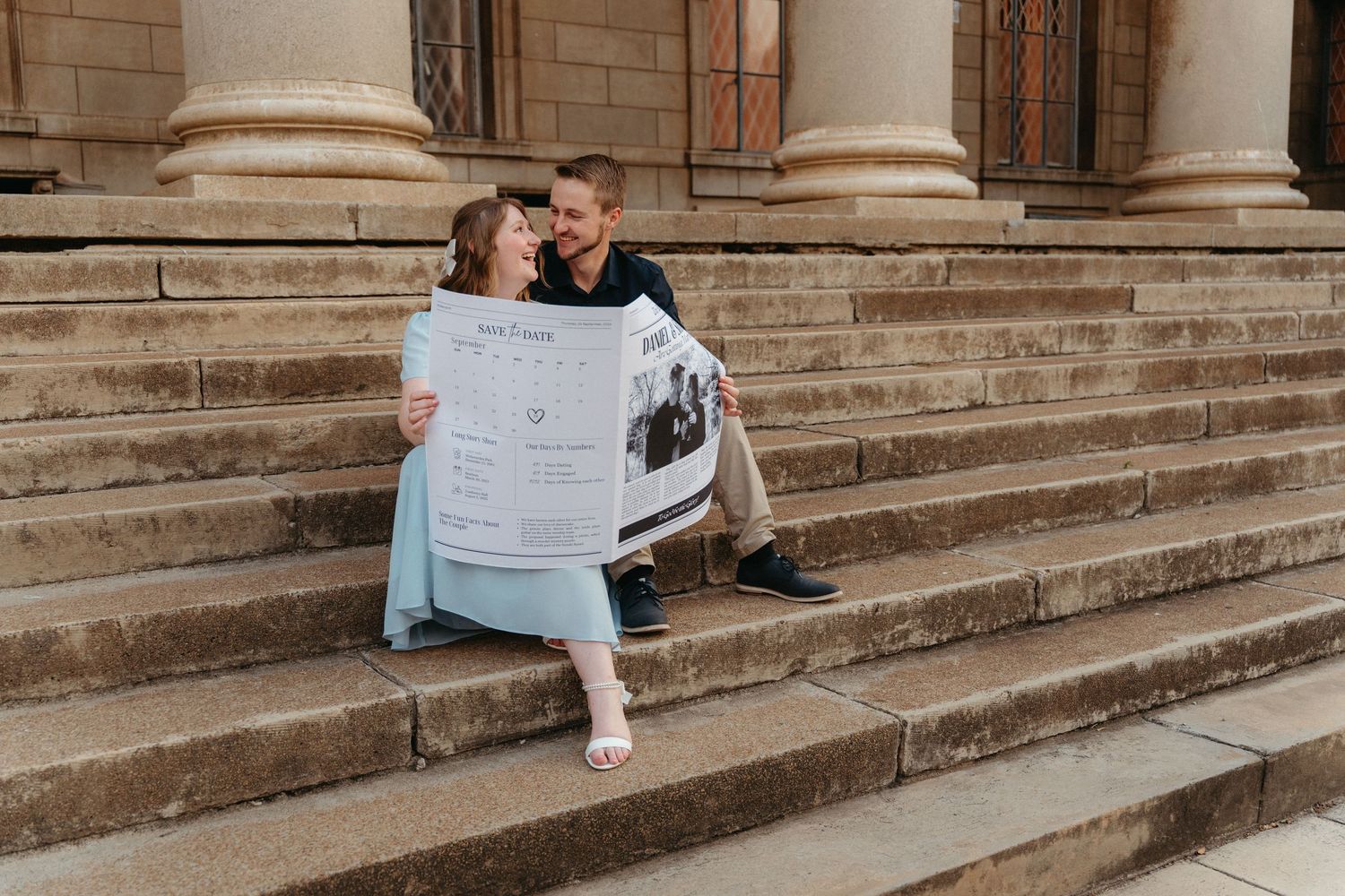 A couple sits together on stone steps reading a newspaper while dressed in formal attire.