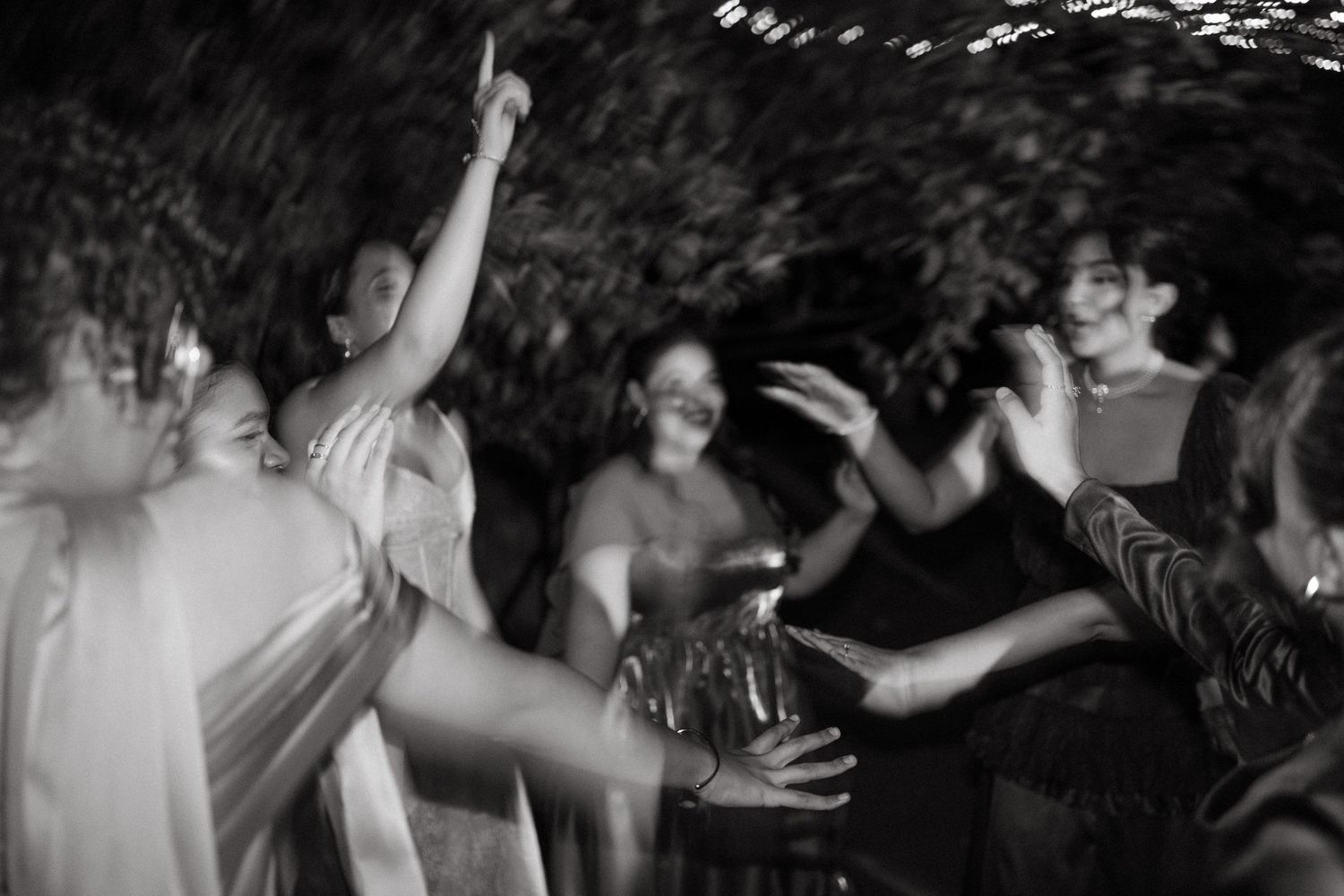 Black and white photo of people dancing energetically at a party or celebration outdoors at night.