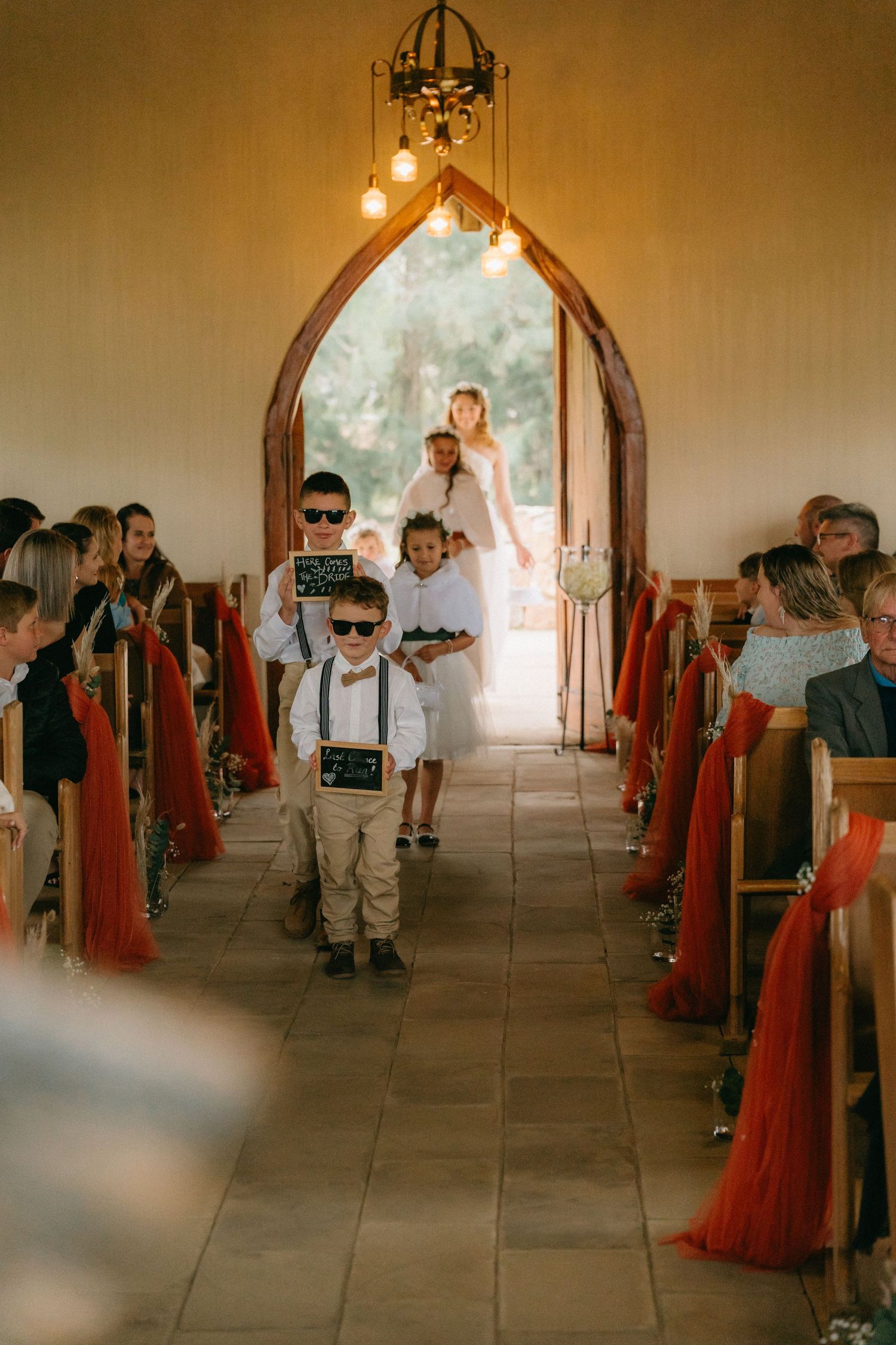 Interior of a chapel with arched windows and red decorative elements during a wedding ceremony.
