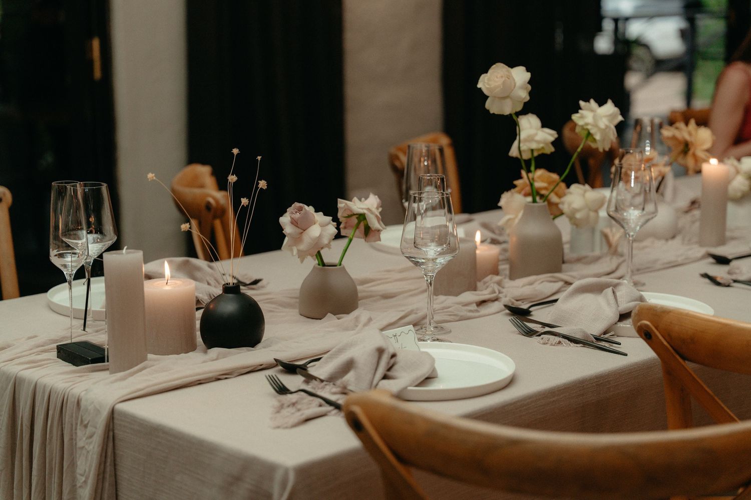 Elegant wedding reception table settings with white linens, candles and rustic decor in a romantic evening atmosphere.