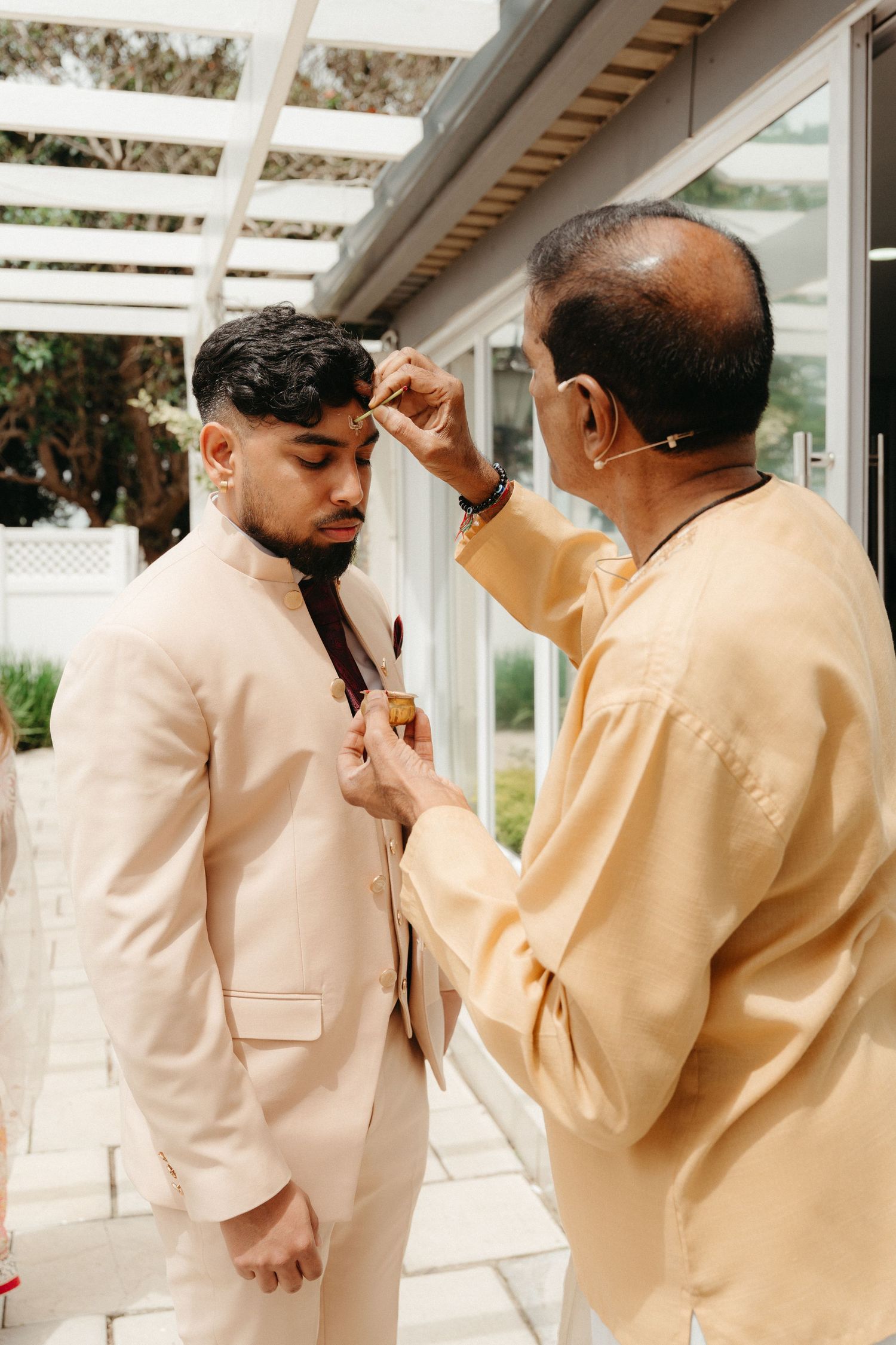 Four sequential photos showing a tender moment between two people in cream-colored formal attire at an indoor venue.