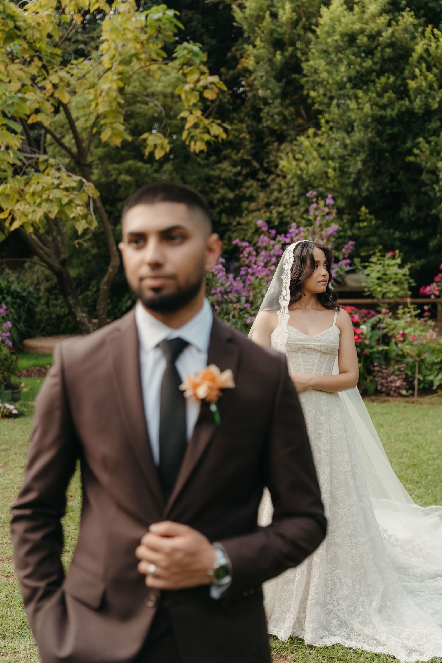Groom in brown suit with bride in lace dress in Beechwood Gardens, Johannesburg