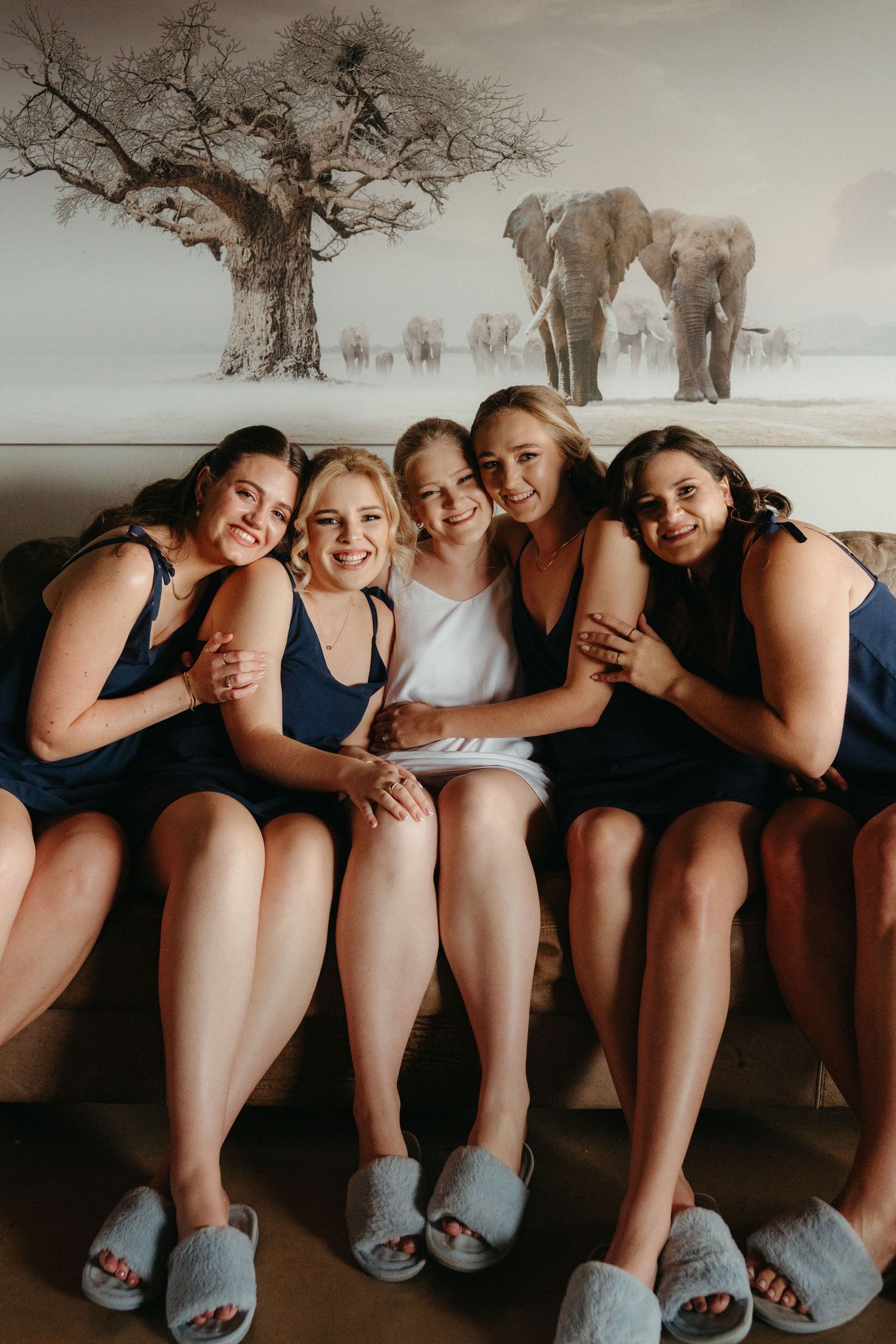 Group photo showing slippers and legs with elephants in background artwork.