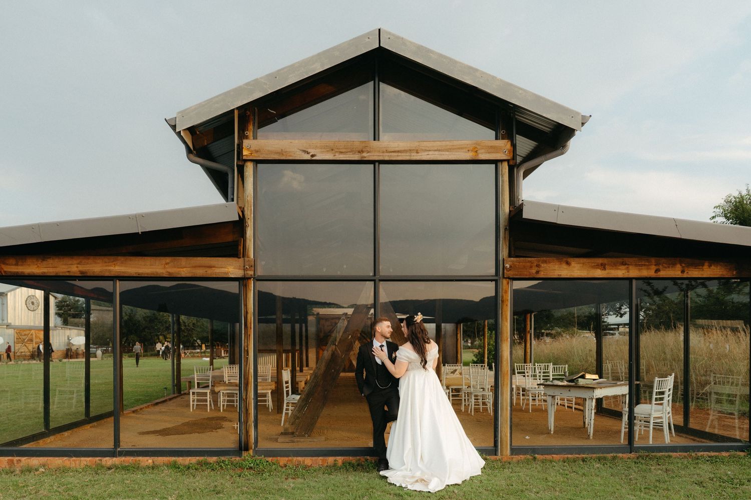A modern barn-style wedding venue with glass walls surrounded by countryside.