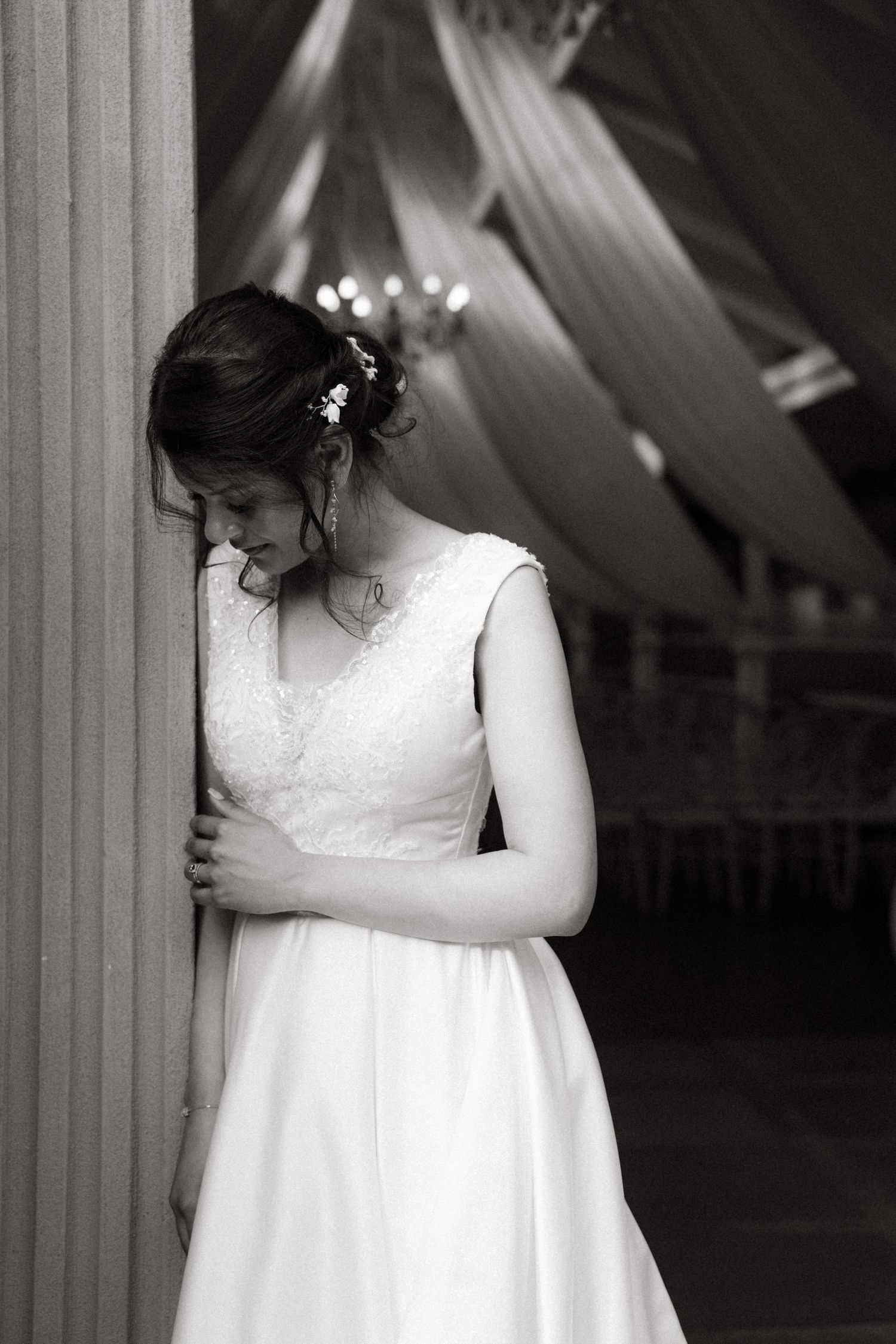 Indoor wedding portraits with elegant white gown and draped fabric creating a dramatic black and white series.