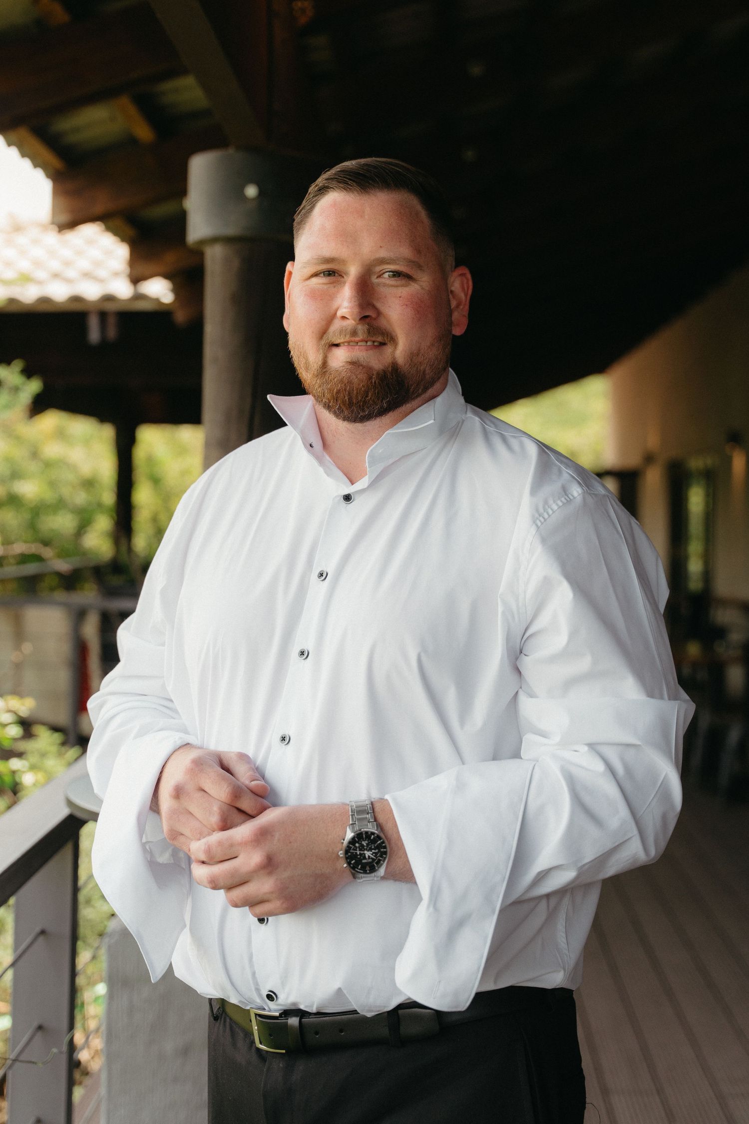 Four sequential photos show someone in a white dress shirt and black cap adjusting their sleeves outdoors on a porch.