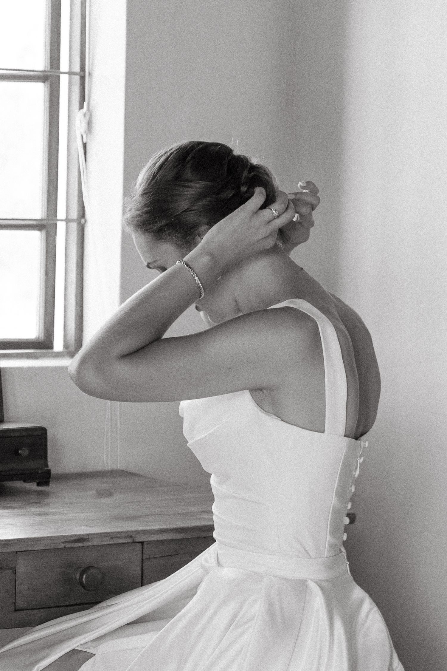 A series of black and white photos showing someone in a white dress adjusting their hair in different poses.
