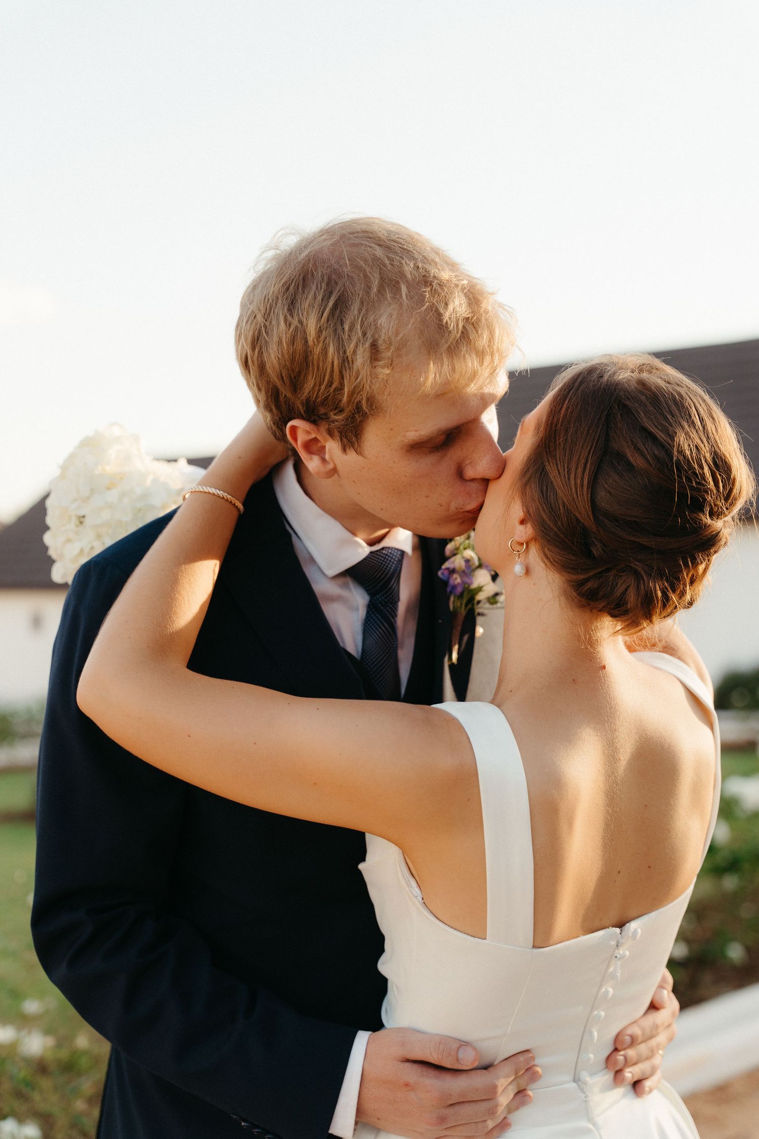 A romantic wedding couple shares intimate kisses in a series of four connected outdoor portrait photographs.