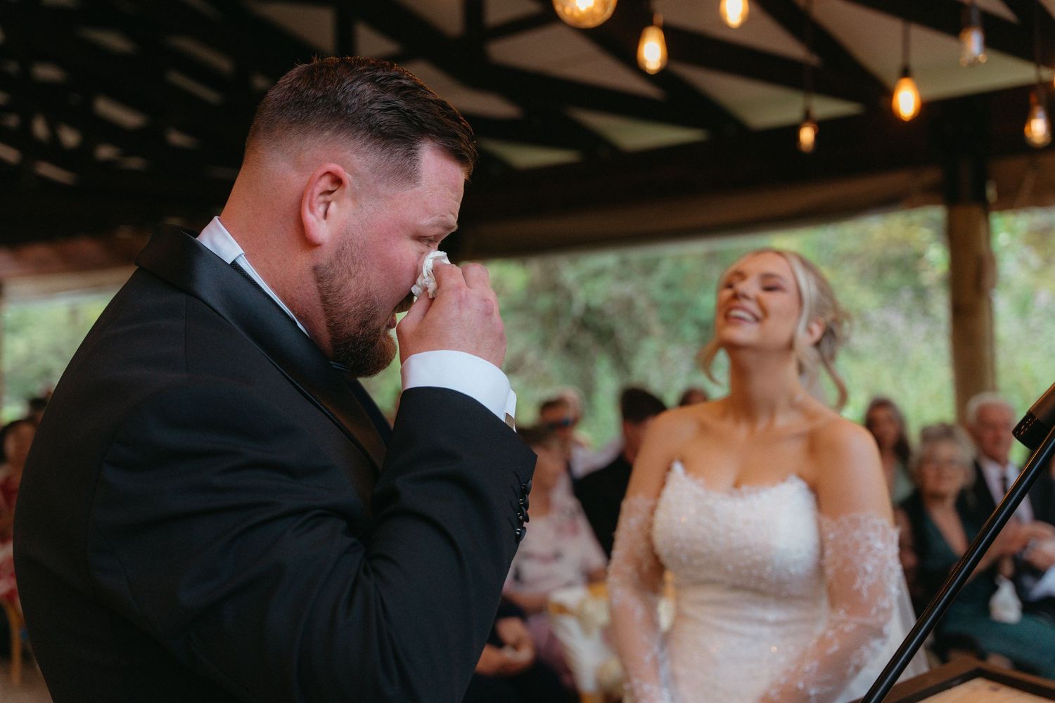 A joyful wedding couple shares an intimate moment on the dance floor during their first dance at a rustic reception.