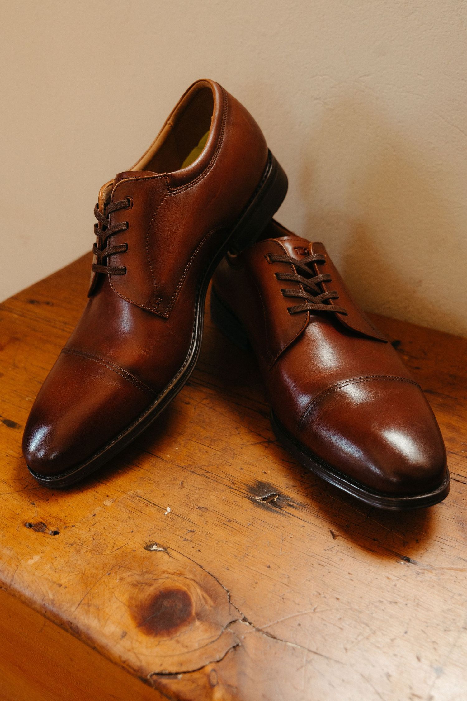 Groom's brown leather dress shoes arranged in different angles on a wooden surface at Steynshoop Lodge