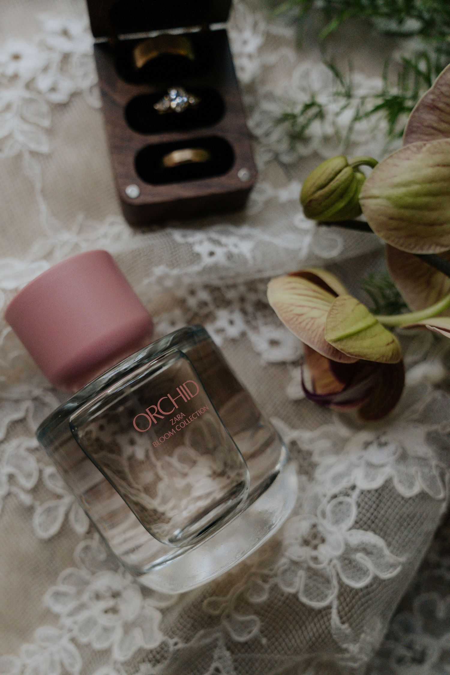 Perfume bottles arranged on delicate lace fabric with soft lighting and floral elements.