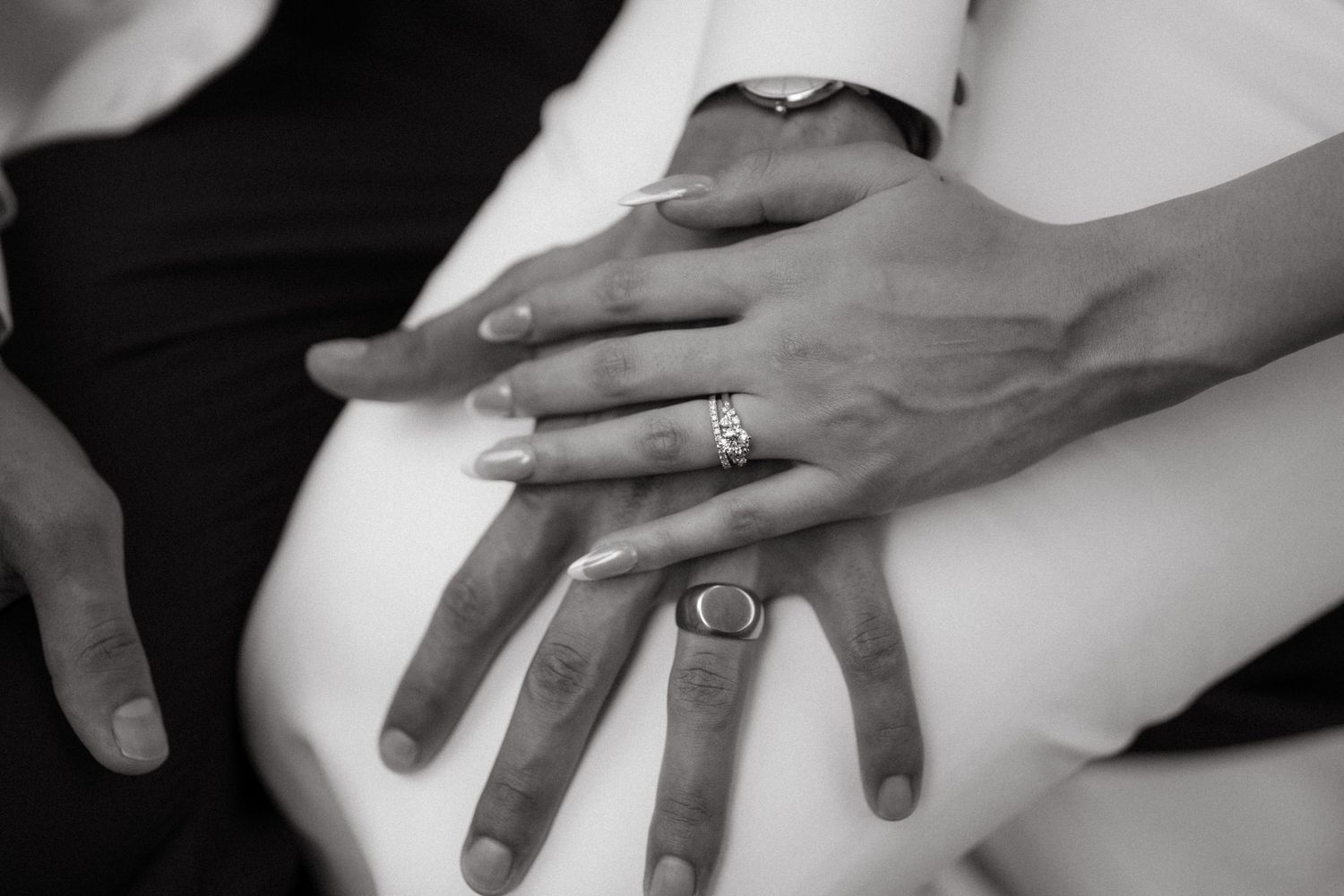 Black and white close-up of newlywed couple's hands showing wedding rings.