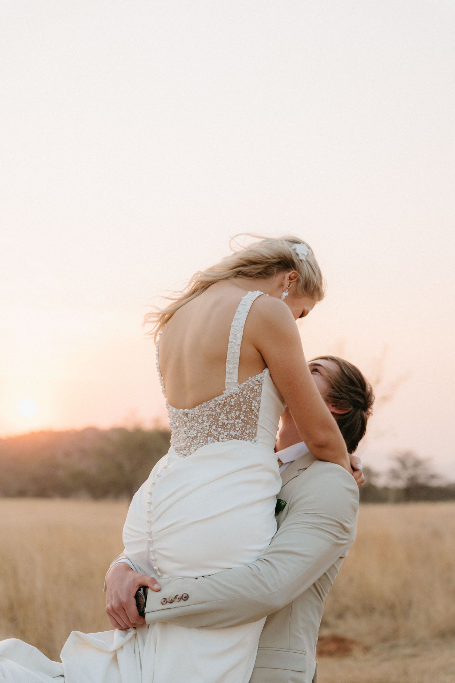 A couple embraces in a romantic sunset moment in a golden field.