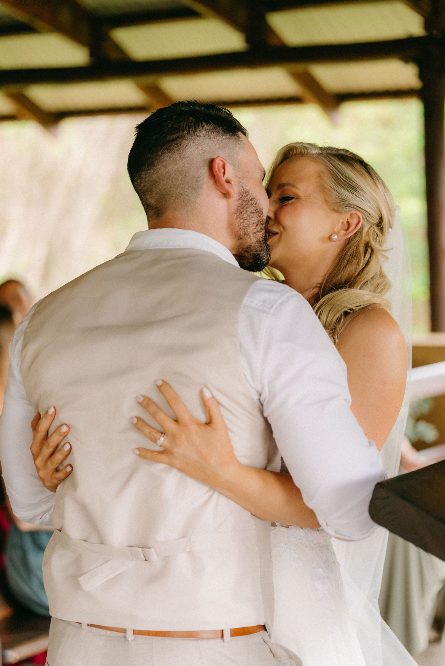 A romantic first dance moment captured under a rustic wooden shelter.