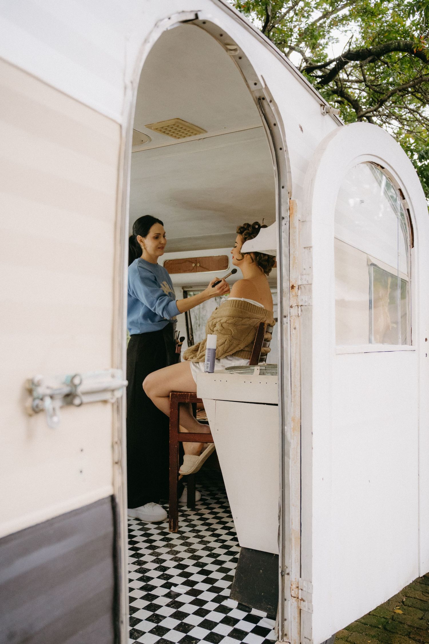 A vintage mobile beauty salon setup in a retro trailer with black and white checkered flooring.