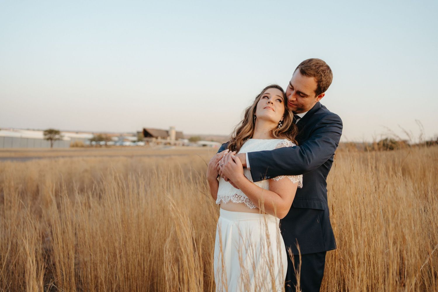 Intimate embrace captured in a golden wheat field during sunset.